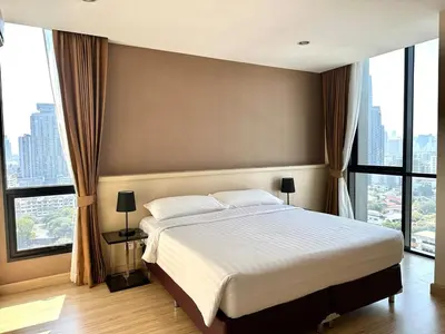 a bedroom with a large bed and large windows at Spacious Serviced Apartment! in Bangkok