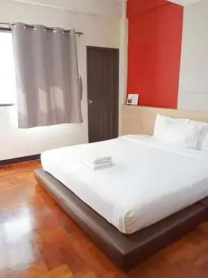 a bedroom with a large white bed with a red wall at XX GO INN BTS Silom - Saint Louis สถานีรถไฟฟ้าเซนต์หลุยส์ in Bangkok