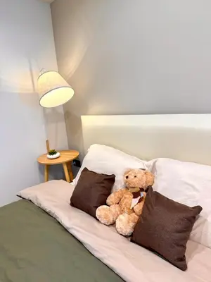 a teddy bear sitting on a bed with pillows at D Glamor Hotel Phutthamonthon Sai 1 ,Southern Bus Terminal, Bangkok in Bangkok