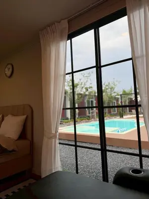 a bedroom with a view of a pool through a window at D Glamor Hotel Phutthamonthon Sai 1 ,Southern Bus Terminal, Bangkok in Bangkok