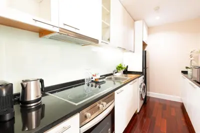 a kitchen with white cabinets and a sink at SkyVillas Residential Apartments in Yan Nawa