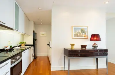 a kitchen with white walls and a table with a lamp at SkyVillas Residential Apartments in Yan Nawa