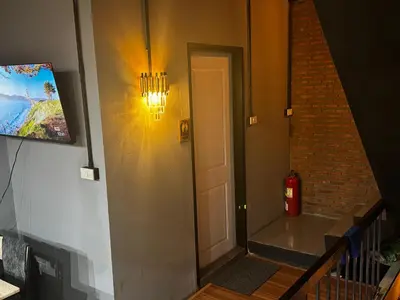 a hallway with a door and a fire extinguisher on the wall at Stay At pan Hostel in Bangkok
