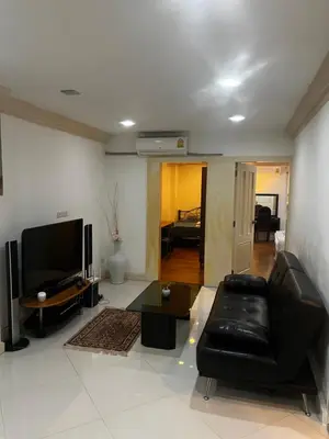 a living room with a black leather couch and a flat screen tv at Euro Classic Condominium in Bangkok