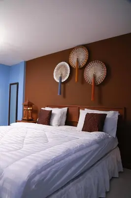 a bedroom with a large bed with white sheets and fans on the wall at UPAR Hotels Silom in Bangkok