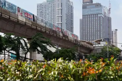 a train on a bridge in a city with tall buildings at Ideo Mobi Condo in Bangkok