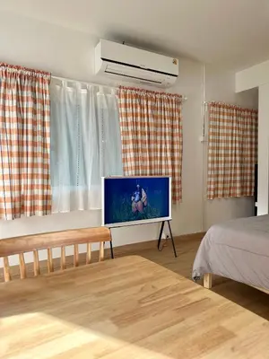 a living room with a flat screen tv and a bed at J House in Nonthaburi