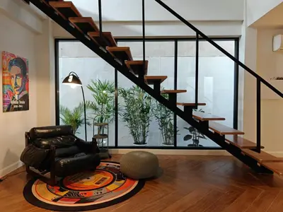 a living room with a chair and a staircase at Thonglor 4-story modern art villa Free WiFi Netflix in Bangkok