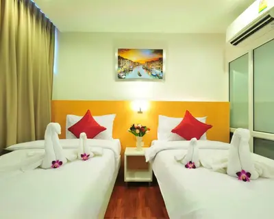 two beds in a hotel room with white and red pillows at Premier Place Bangkok in Bangkok