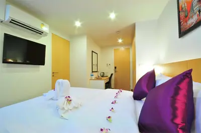 a bedroom with a white bed with purple pillows at Premier Place Bangkok in Bangkok