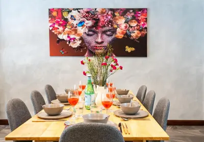 a table with chairs and a painting of a woman with flowers at 3BR design townhouse in central Bangkok - 10min to BTS, Emquartier in Bangkok