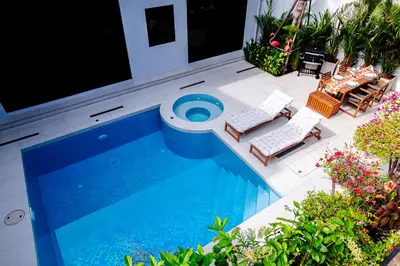 a swimming pool with two chairs and a table at Bangkok Luxury Private Pool & Jacuzzi Villa , Daily Maid in Bang Bua Thong