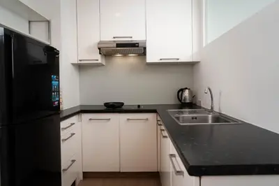 a kitchen with white cabinets and a black refrigerator at Baan K Residence in Bangkok