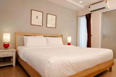 a bedroom with a large white bed and a window at Baan K Residence in Bangkok