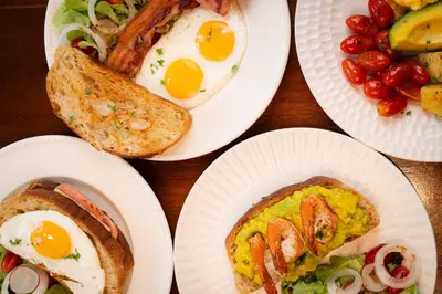 a table with plates of eggs and toast and fruit at Baan K Residence in Bangkok