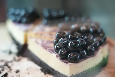 a piece of cake with blueberries on top of it at Baan K Residence in Bangkok