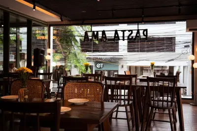 a restaurant with wooden tables and chairs and a large window at Baan K Residence in Bangkok