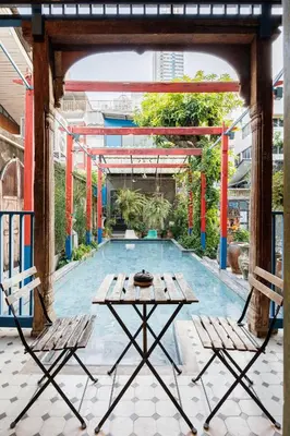 a table and two chairs in front of a pool at The Anonymous House in Bangkok