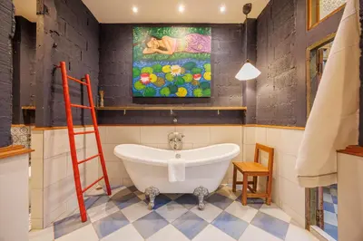a bathroom with a bath tub and a painting on the wall at The Anonymous House in Bangkok