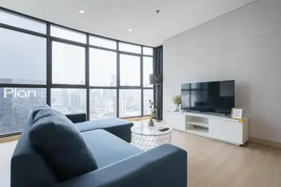a living room with a blue couch and a tv at Phetchaburi - Lumpini Condo in Bangkok