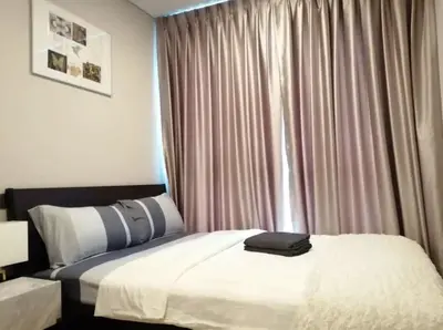 a bedroom with a bed and a window with curtains at Phetchaburi - Lumpini Condo in Bangkok