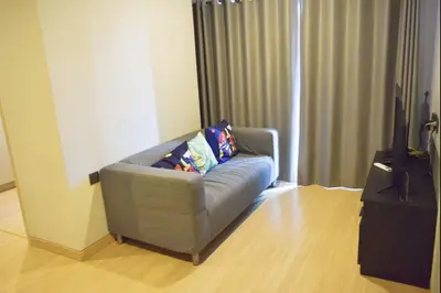 a living room with a couch and a television at Phetchaburi - Lumpini Condo in Bangkok