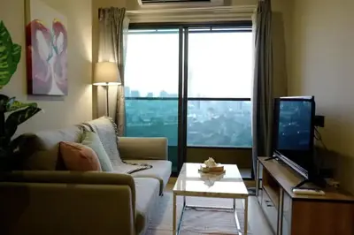 a living room with a couch and a tv at Phetchaburi - Lumpini Condo in Bangkok