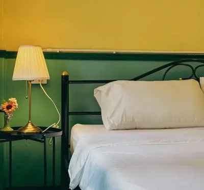 a bedroom with a bed with a green headboard and a lamp at During Moonshine Stay in Bangkok