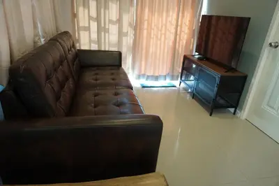 a brown leather couch in a living room with a television at Family Friendly Home in Bangna