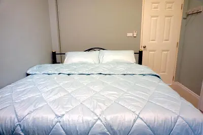 a bed with a white comforter in a bedroom at Family Friendly Home in Bangna