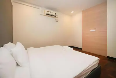 a bedroom with a white bed and a wooden door at XX GO INN Silom BTS Surasak - สุรศักดิ์ in Bangkok