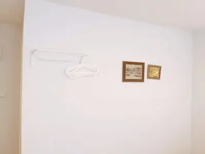 a white wall with two pictures and a hanger at XX Mitr Inn Yaowarat China town -มิตร อินน์ เยาวราช in Bangkok