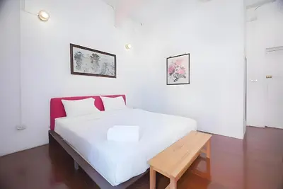 a white bedroom with a white bed and a wooden bench at XX Mitr Inn Yaowarat China town -มิตร อินน์ เยาวราช in Bangkok