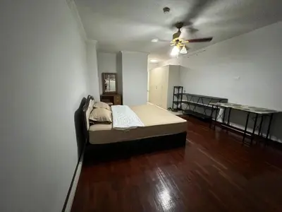 an empty room with a bed and a table at Srivara condo Rachada in Bangkok