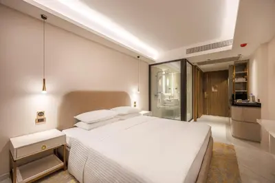 a bedroom with a large white bed and a kitchen at Wanda Jin Residences The Ease Sierra Bangkok in Bangkok
