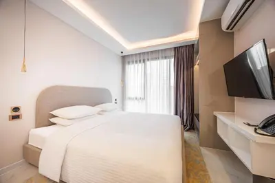 a bedroom with a white bed and a television at Wanda Jin Residences The Ease Sierra Bangkok in Bangkok