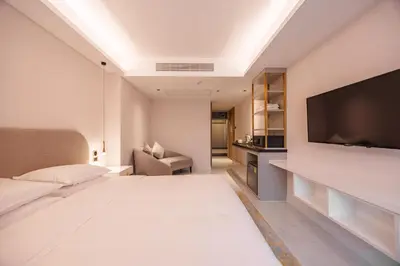 a hotel room with a large bed and a flat screen tv at Wanda Jin Residences The Ease Sierra Bangkok in Bangkok
