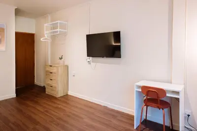 a room with a desk and a television on a wall at Liver Bird Ratchada in Bangkok