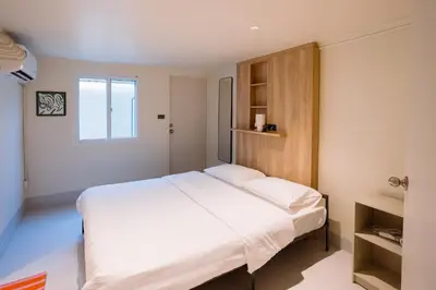 a bedroom with a large white bed and a window at Liver Bird Ratchada in Bangkok