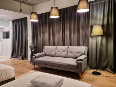 a living room with a couch in front of curtains at Human Touch Room - Soulful Bangkok Hideout in Lat Krabang