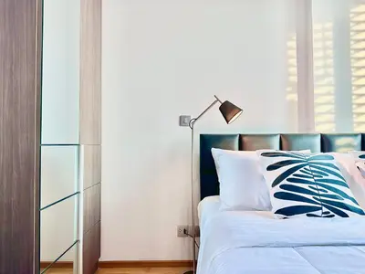 a bedroom with a bed with a blue headboard and a lamp at Luxury 2Bed Duplex - 1min From Thonglor BTS in Bangkok