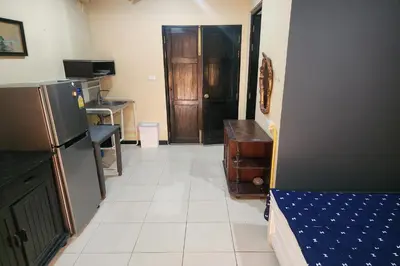 a room with a kitchen with a refrigerator and a door at Baan Nara 15 in Bangkok