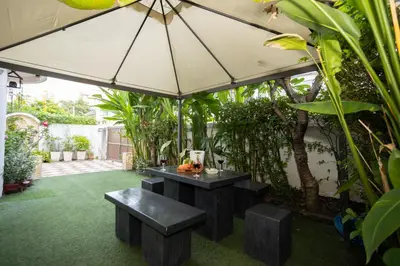 a patio with a table and benches under an umbrella at Low-Rise House for Groups Near BTS & EmDistrict For Spacious Cozy Stay in Bangkok