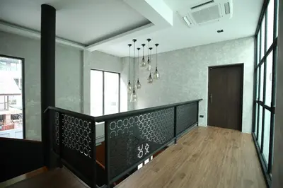 a hallway with a wooden floor and a staircase with windows at Chic Ekkamai Escape Near BTS, Dining & Nightlife in Bangkok