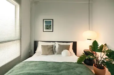 a bedroom with a bed with white sheets and a plant at nap in a blue moon in Bangkok