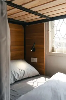 a bed with a wooden head board and a window at nap in a blue moon in Bangkok