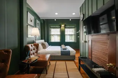 a bedroom with green walls and a bed and a couch at Arun Sa Wad - Yaowarat 27 in Bangkok