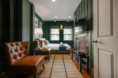 a bedroom with green walls and a bed and a couch at Arun Sa Wad - Yaowarat 27 in Bangkok