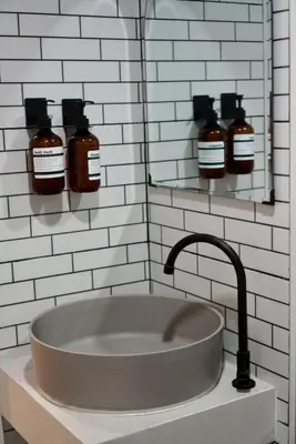 a bathroom sink with three bottles on a wall at Around Ari Hostel in Bangkok