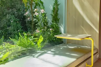 a yellow table sitting in front of a garden at jasminespace in Khlong San